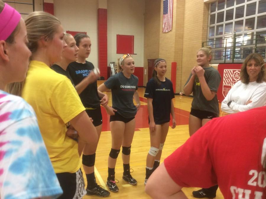 The Regis Jesuit girls volleyball huddles around Coach Dunston as they practice before regionals.