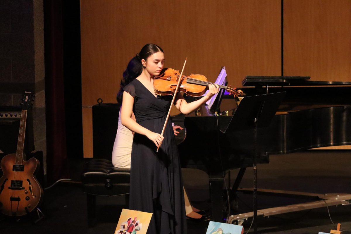 Jasmine Munn '25, performs a duo, strumming her violin, with Jenna Kim '25, playing the piano.